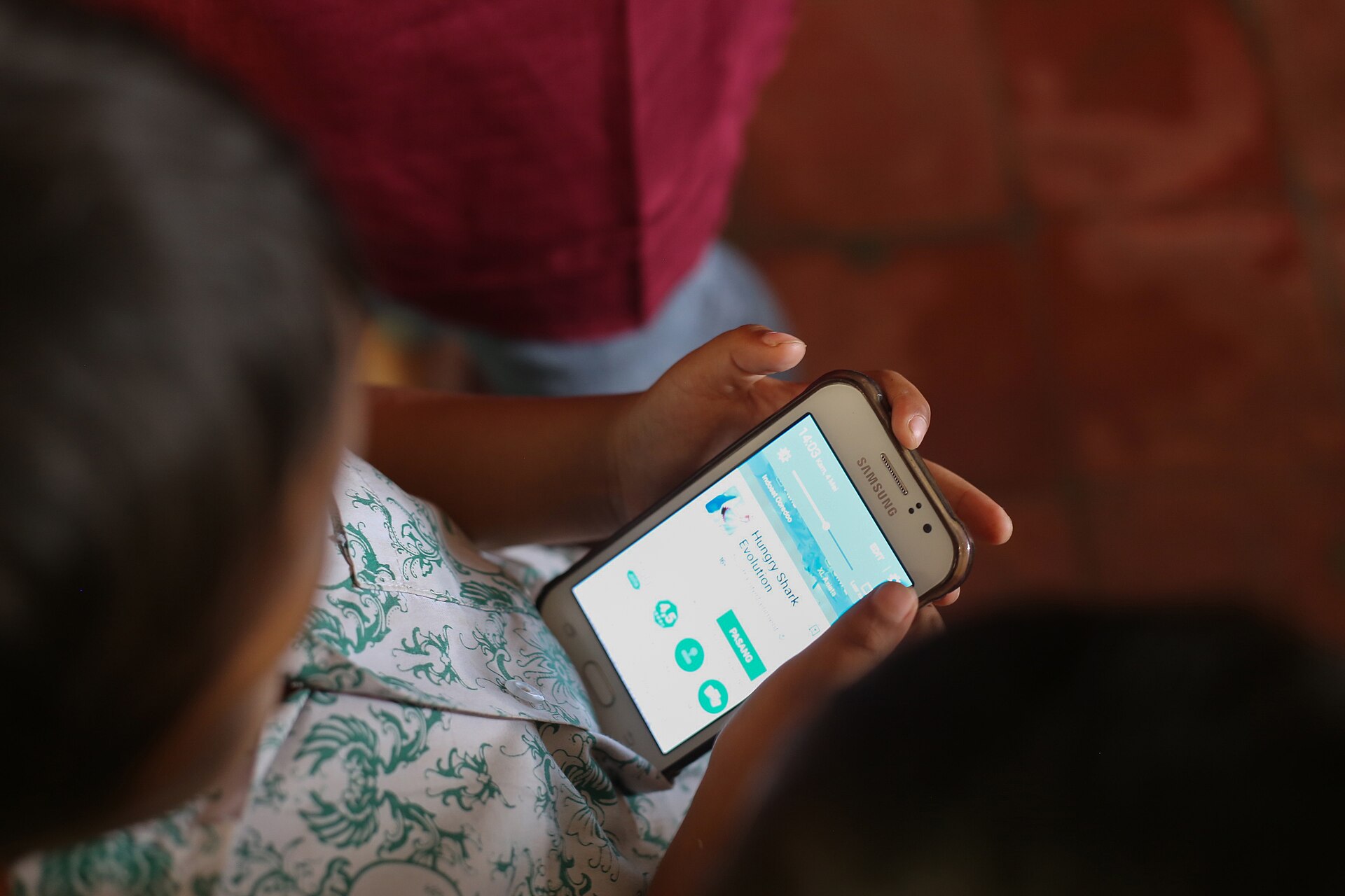 মোবাইল ফোন হাতে একটি শিশু, মুখ দেখা যাচ্ছে না