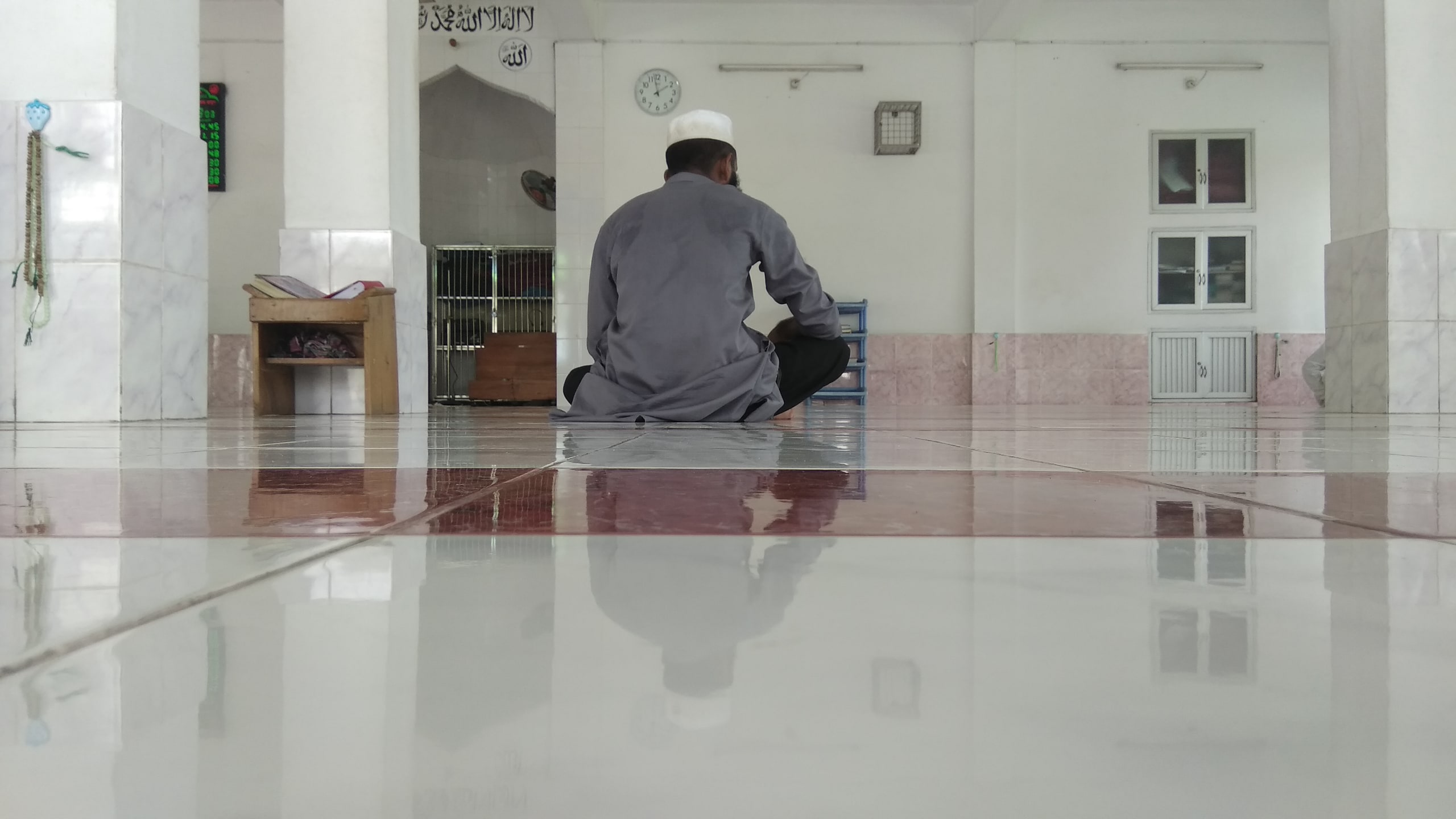 মসজিদে বসে কোরআন পড়ছেন একজন